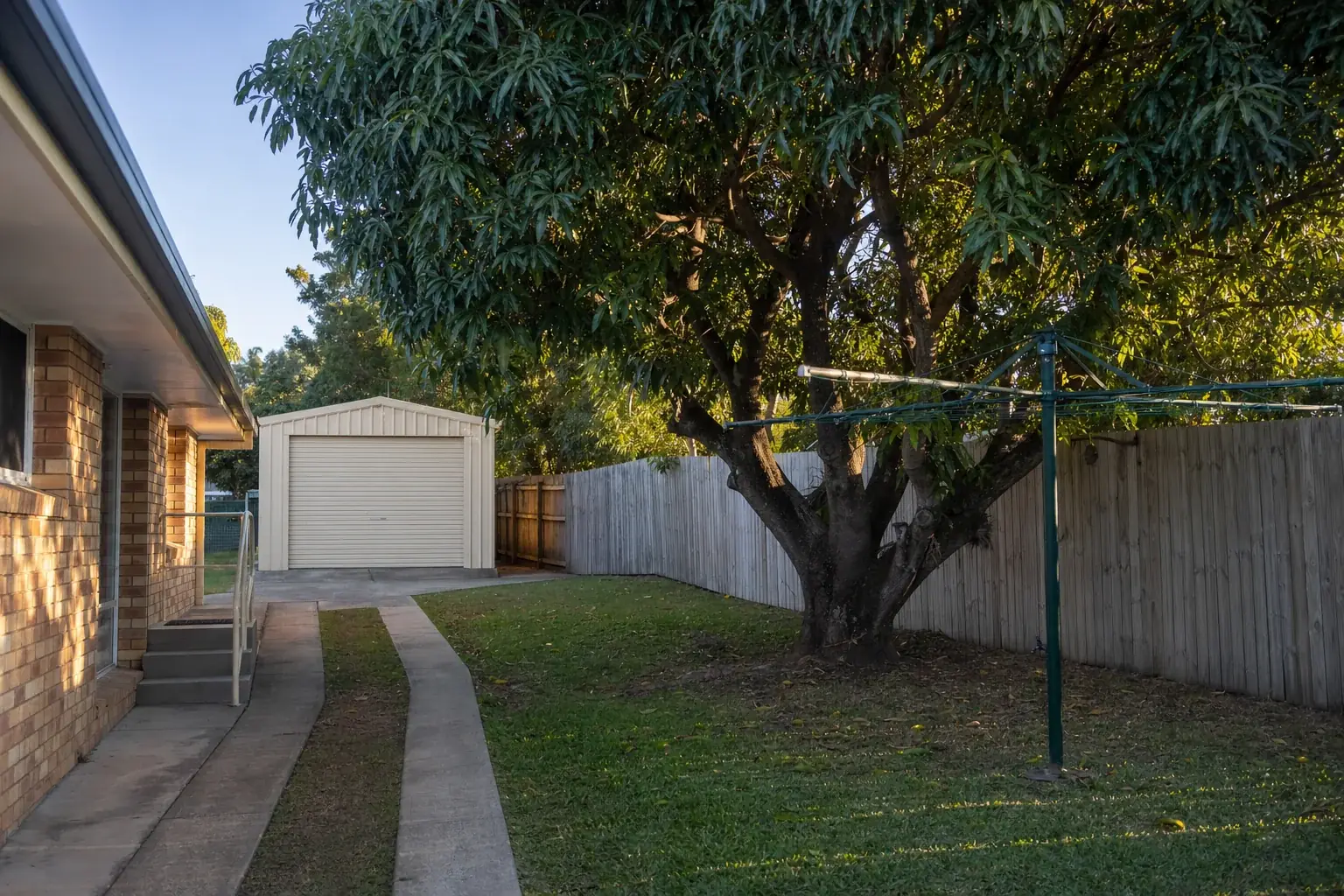 Cream garage shed at the end of a narrow side driveway behind an older brick house in Southport